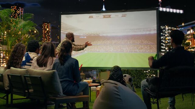 Upset spectators watch a live football match on a projection screen and argue about player performance while analyzing tactics during the soccer broadcast.