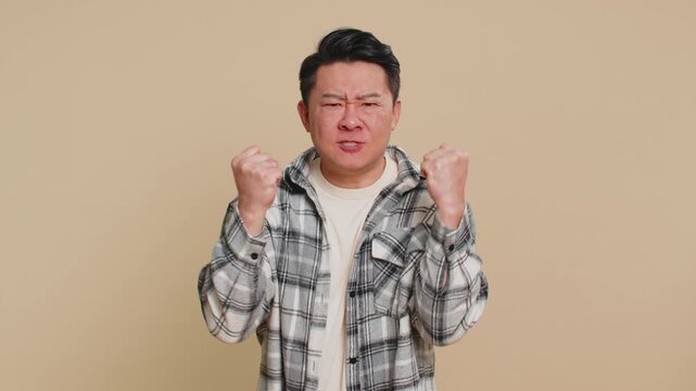Upset frustrated annoyed Asian middle-aged man raising hands in indignant expression, quarreling, asking reason of conflict, why such stubborn. Adult mature Chinese guy isolated on beige background