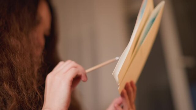 Woman examines papers. Woman holds open folders while pointing out details on documents inside them. scene is focused on hands and materials with soft indoor lighting