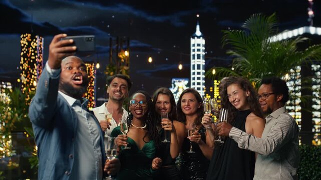 Happy friends gather for smartphone selfie at festive rooftop party