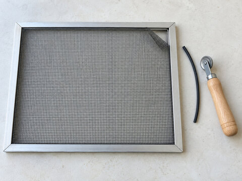 Window insect screen with lifted mesh corner and spline repair tools