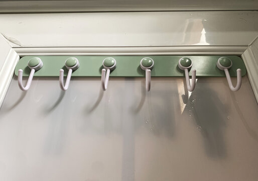 Modern plastic rail mounted on the bathroom ceramic tile wall. towels and clothes.