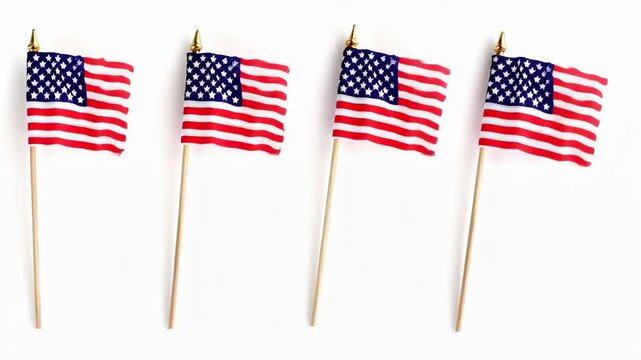 Row of four small American flags on wooden poles against a white background