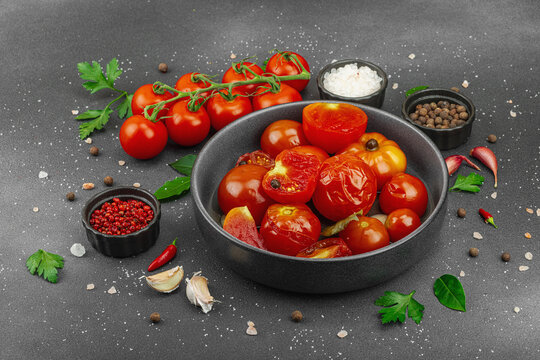 Lacto-fermented probiotic tomatoes in a bowl with garlic and spices, with fresh vine tomatoes