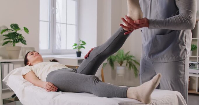 Manual therapy exercise, leg rehabilitation in clinic, physical therapist manipulative therapy, female patient lying on med coach, massage after sport trauma, reduce disability, improve joint mobility