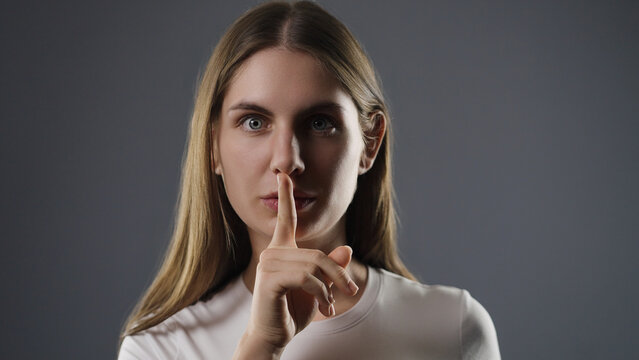 Young woman with finger on lips asking for silence and privacy