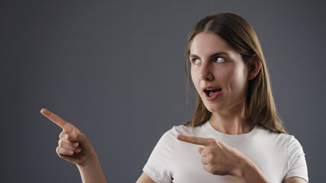 Young woman pointing fingers showing direction, gesturing with an expressive face