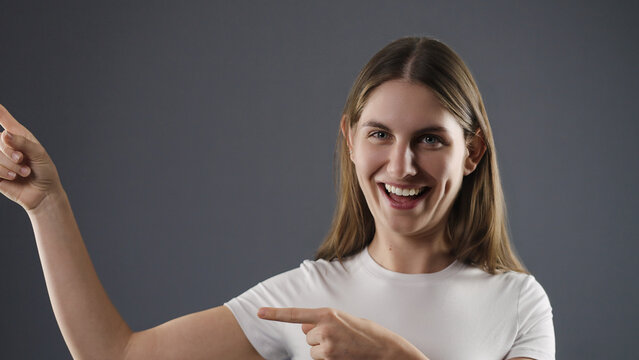 Happy woman laughing and gesturing with both hands, pointing to something interesting