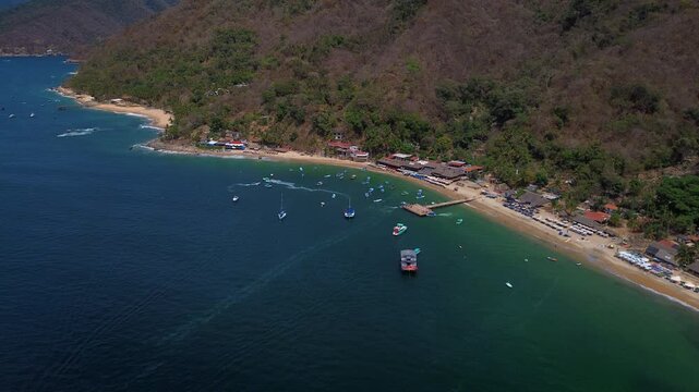 Las Animas pier with boats yachts and jet skis in Puerto Vallarta Mexico surrounded by calm blue ocean waters tropical beach landscape and holiday travel activities aerial drone view