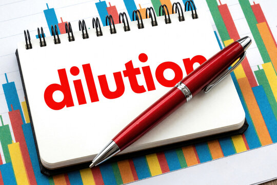 Red word dilution written on open notebook. Red pen lies on notepad over colorful financial stock market chart. Concept of share dilution, stock value decrease, finance risk, investment loss in