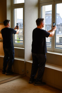 Man captures city view through tall window