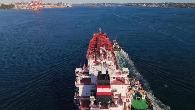 Fuel transport tanker entering Halifax Harbour at the port of Nova Scotia, Canada, captured from above with two tugboats assisting and guiding the large vessel toward the terminal.