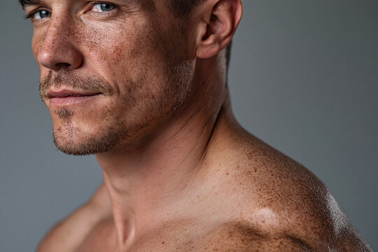 Freckled male shoulder catching light angle highlight moving freckle male shoulder skin portrait close up profile stubble blue eye texture light highlight studio gray background muscular bare