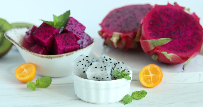 Woman taking piece of pitahaya at white table, closeup