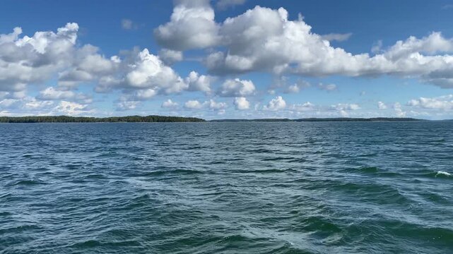 Far-reaching view over a calm sea with blue sky and white clouds, ferry trip, archipelago around Turku, Finland