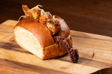 Close-up of a shrimp and octopus seafood sandwich on a wooden board. © mario