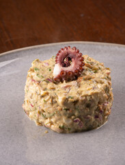 Close-up of seafood tartare garnished with a gourmet octopus tentacle. © mario