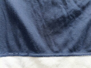 Close-up texture of dark navy blue fleece fabric with stitched bottom hem © Salman