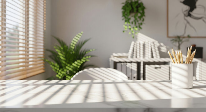 Pencils on a white marble desk with window blind shadows in a sunny room