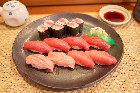 Premium Aomori tuna sushi platter with fatty Otoro, medium Chutoro, and lean Akami nigiri, plus maki rolls, on a black plate in an authentic Japanese dining setting.