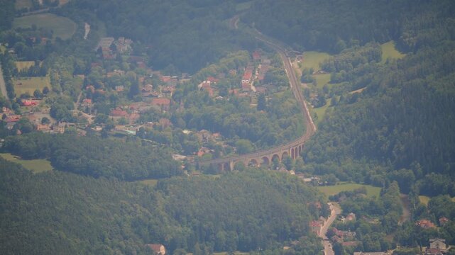 Aerial view of a town amid mountains and greenery with winding roads.