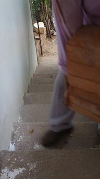 Young Worker Carrying Heavy Bricks Climbing Stairs at Worksite