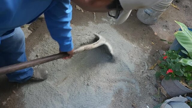 Young Man Mixing Cement and Sand using Shovel on Ground