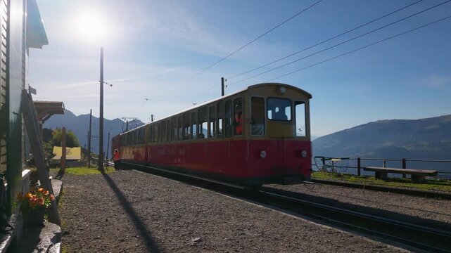 Historic Schynige Platte cogwheel train in the Bernese Oberland, Switzerland, showing traditional red and cream railway carriages against a Alpine mountain backdrop