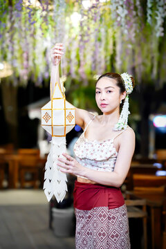 Asian woman in traditional Northern Thai dress holding a Lanna paper lantern.