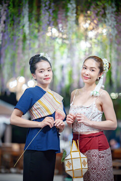 Asian woman in traditional Northern Thai dress holding a Lanna paper lantern.