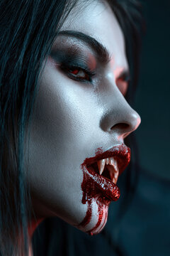 A striking portrait of a female vampire with piercing red eyes, sharp fangs dripping with blood, and dramatic gothic makeup embodies the alluring and terrifying essence of the supernatural.