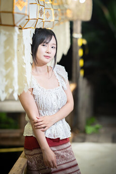Asian woman in traditional Northern Thai dress and a Lanna paper lantern.