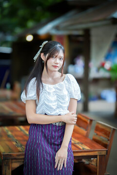 a beautiful Asian woman in traditional Thai attire posing gracefully outdoors.