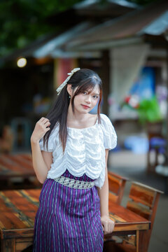 a beautiful Asian woman in traditional Thai attire posing gracefully outdoors.