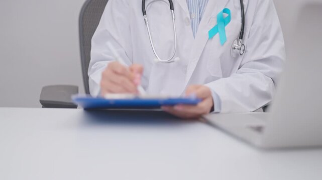 doctor using laptop and report notes on notebook. blue Ribbon concept of November Prostate Cancer Awareness month, Diabetes day , Men Health, International men, Father day. world cancer day