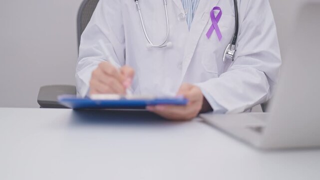 doctor using laptop and report notes on notebook. purple ribbon for concept of Violence, Pancreatic, Esophageal, Testicular cancer, Alzheimer, Epilepsy, Lupus, Crohn and Fibromyalgia. Awareness month