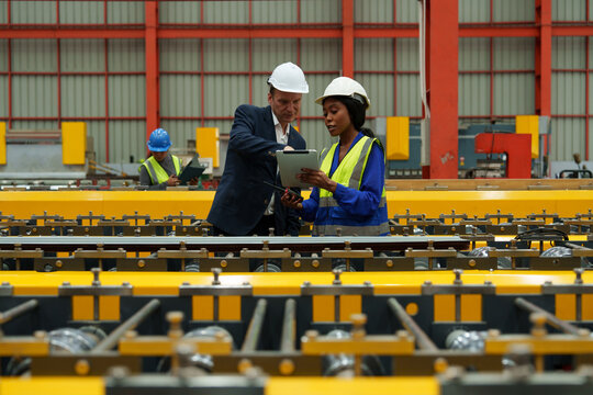Engineers and staff are inspecting the assembly line system in a metal sheet and metal roofing manufacturing plant.
