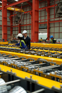 Engineers and staff are inspecting the assembly line system in a metal sheet and metal roofing manufacturing plant.