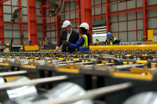 Engineers and staff are inspecting the assembly line system in a metal sheet and metal roofing manufacturing plant.