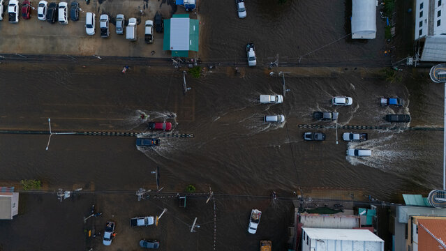 An elevated view of a flooded road with vehicles driving through the water.	