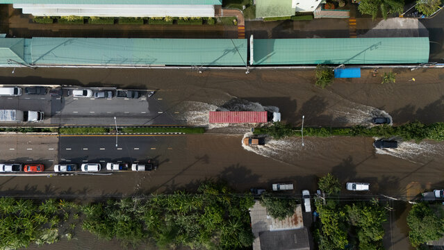 An elevated view of a flooded road with vehicles driving through the water.	