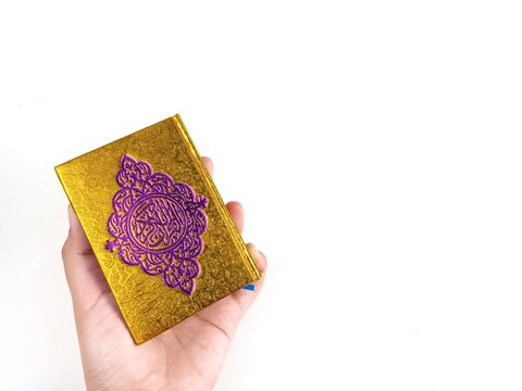 The Quran being held by hand with an isolated white background. It is the holy book that guides Muslims.