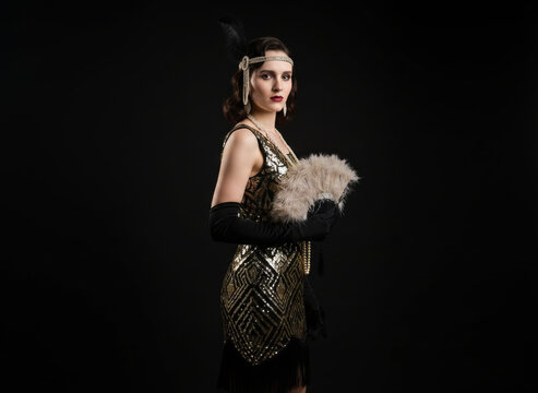 Glamorous 1920s Gatsby woman in gold and black Art Deco dress with feather fan