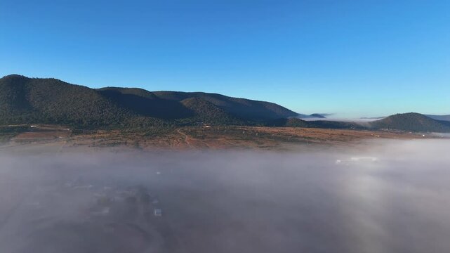 Panoramic aerial view of mountain range rising above low morning fog inversion layer in Coahuila Mexico