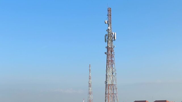 Feeling connected and hopeful as red and white telecommunication towers with antennas rise tall against a clear blue sky