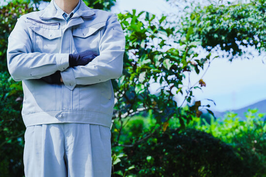 自然の背景で腕組みする作業服の男性
