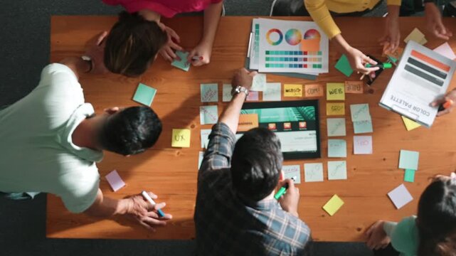 Time lapse of business people working together to design web design. Aerial view of designer brainstorming and discussing about website interface and looking at tablet with digital design. Symposium.