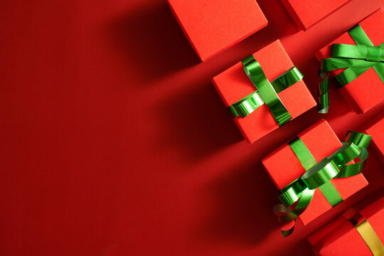 Red Christmas gift boxes with green ribbons on red background with copy space