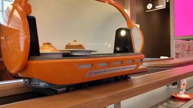 Hand taking plated food from an automated restaurant serving robot, showing modern food service technology and restaurant a