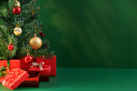 Decorated Christmas tree with wrapped gifts on green copy space background
